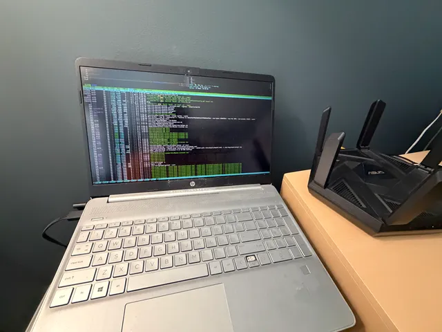 The HP laptop running htop beside a router.
